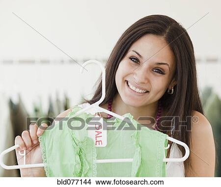 Picture - Mixed race woman shopping in clothing store. Fotosearch