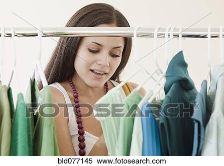 Stock Photography - Mixed race woman shopping in clothing store. Fotosearch