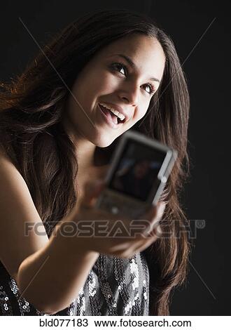 Stock Image - Mixed race woman using digital camera. Fotosearch