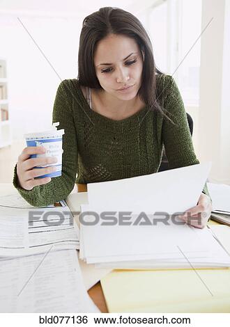 Stock Photograph - Mixed race woman working and drinking coffee. Fotosearch