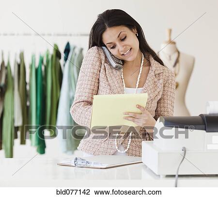 Stock Image - Mixed race woman working on clothing shop. Fotosearch