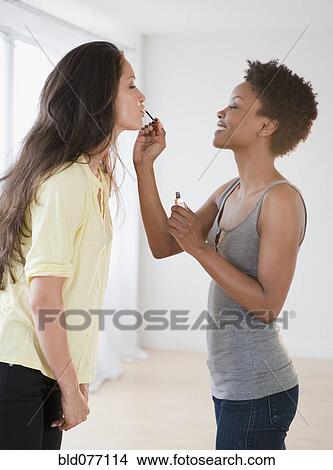 Woman putting lip gloss on friend View Large Photo Image Picture - Woman putting lip gloss on friend. Fotosearch