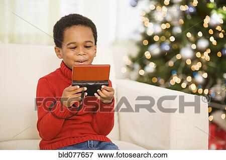 African boy playing video game at Christmas View Large Photo Image Stock Photo - African boy playing video game at Christmas. Fotosearch