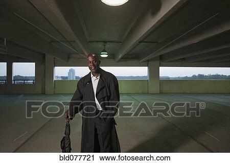 Stock Image - African businessman standing in parking garage. Fotosearch