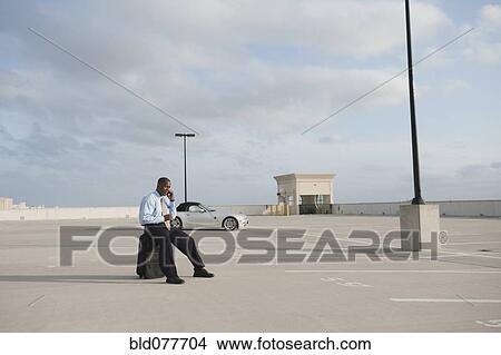 Picture - African businessman waiting in parking lot. Fotosearch