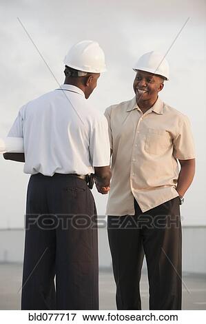 Stock Photo - African businessmen in hard-hats shaking hands. Fotosearch