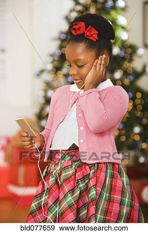 Stock Photo - African girl listening to mp3 player at Christmas. Fotosearch
