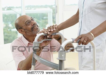 Stock Photo - African man encouraging wife using walker. Fotosearch
