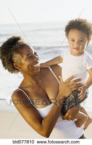 African mother holding son on beach View Large Photo Image Stock Image - African mother holding son on beach. Fotosearch