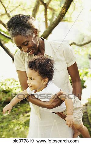 Stock Photo - African woman playing with son outdoors. Fotosearch