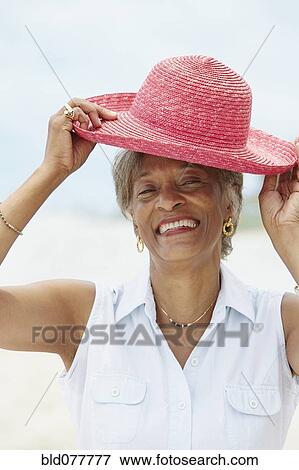 Stock Photo - African woman putting on straw hat. Fotosearch