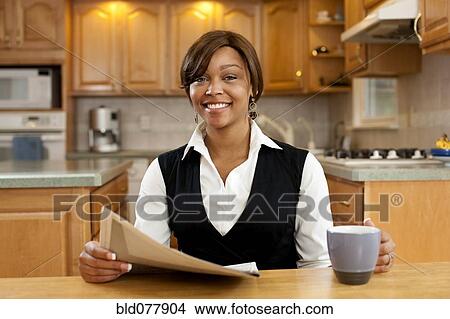 African woman reading newspaper and drinking coffee in kitchen View Large Photo Image Picture - African woman reading newspaper and drinking coffee in kitchen. Fotosearch