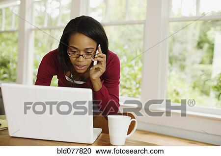African woman talking on cell phone and using laptop View Large Photo Image Stock Image - African woman talking on cell phone and using laptop. Fotosearch