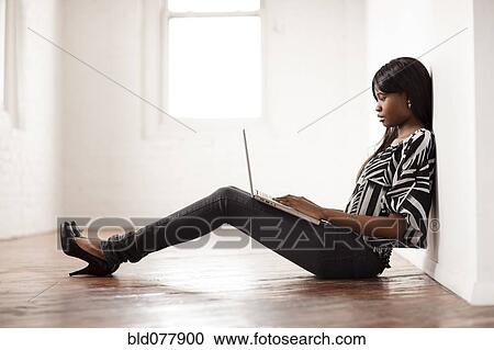African woman using laptop on floor of empty room View Large Photo Image Stock Image - African woman using laptop on floor of empty room. Fotosearch