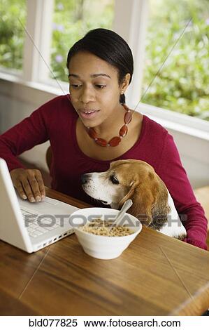 Stock Photography - African woman with dog looking at laptop. Fotosearch