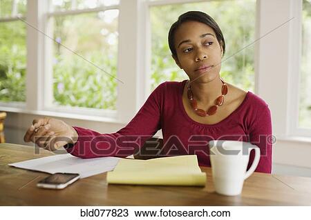 Stock Image - African woman working at table. Fotosearch