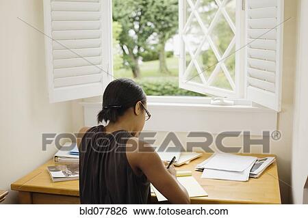 Stock Photograph - African woman writing at desk. Fotosearch