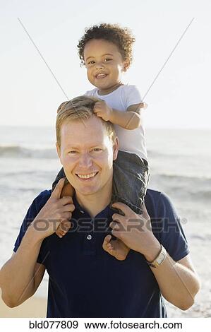 Caucasian father carrying mixed race son View Large Photo Image Stock Photo - Caucasian father carrying mixed race son. Fotosearch