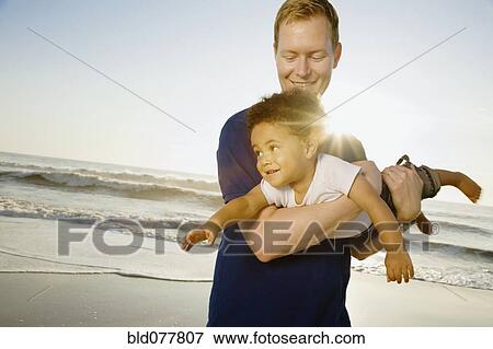 Father playing with mixed race son at beach View Large Photo Image Stock Photo - Father playing with mixed race son at beach. Fotosearch