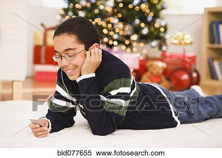 Stock Photography - Hispanic boy listening to mp3 player at Christmas. Fotosearch