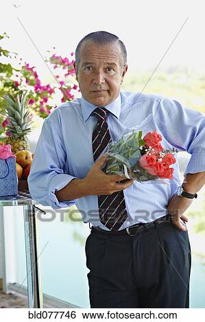 Stock Photograph - Hispanic businessman holding bouquet of flowers. Fotosearch