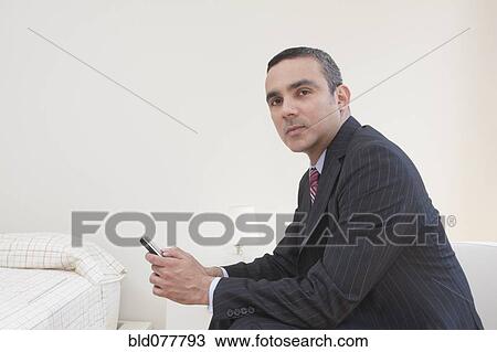 Stock Image - Hispanic businessman holding cell phone. Fotosearch