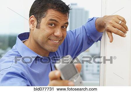 Stock Image - Hispanic businessman text messaging on cell phone. Fotosearch