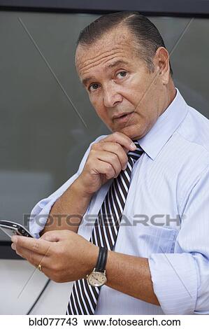 Stock Image - Hispanic businessman using cell phone. Fotosearch