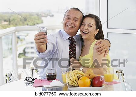 Stock Image - Hispanic couple taking self-portrait with cell phone. Fotosearch