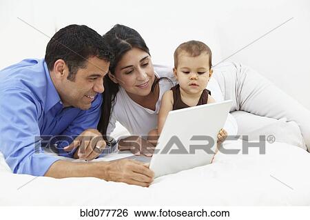 Stock Photograph - Hispanic family looking at laptop. Fotosearch