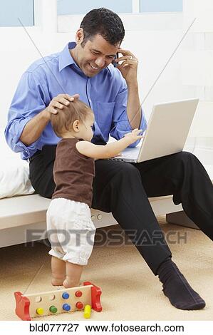 Hispanic father watching daughter and using laptop View Large Photo Image Stock Photo - Hispanic father watching daughter and using laptop. Fotosearch