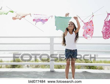 Picture - Hispanic girl hanging laundry to dry. Fotosearch