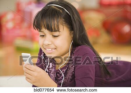 Picture - Hispanic girl listening to mp3 player. Fotosearch