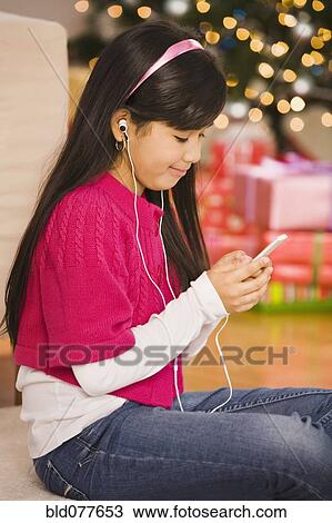 Hispanic girl listening to mp3 player at Christmas View Large Photo Image Stock Image - Hispanic girl listening to mp3 player at Christmas. Fotosearch