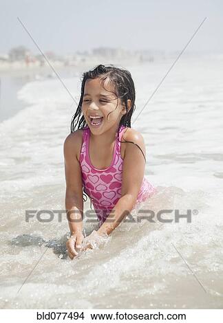Picture - Hispanic girl playing in ocean. Fotosearch