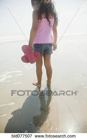 Stock Photo - Hispanic girl walking on beach. Fotosearch