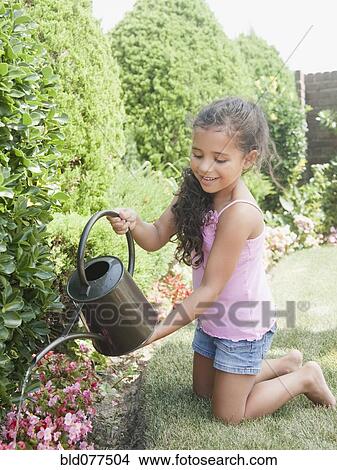 Picture - Hispanic girl watering flowers. Fotosearch