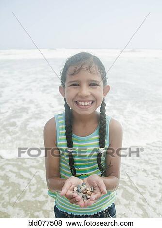 Stock Photo - Hispanic holding pebbles at beach. Fotosearch