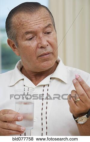 Hispanic man taking pill with water View Large Photo Image Stock Photo - Hispanic man taking pill with water. Fotosearch