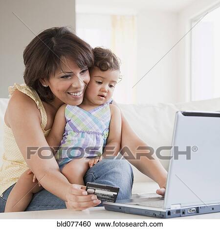 Stock Image - Hispanic mother and daughter looking at laptop. Fotosearch