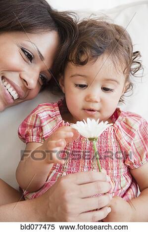 Stock Photography - Hispanic mother and daughter looking at flower. Fotosearch