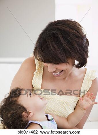 Stock Image - Hispanic mother smiling at daughter. Fotosearch