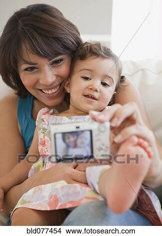 Picture - Hispanic mother taking self-portrait with daughter. Fotosearch