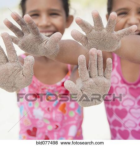 Stock Photo - Hispanic sisters displaying sand-covered hands. Fotosearch