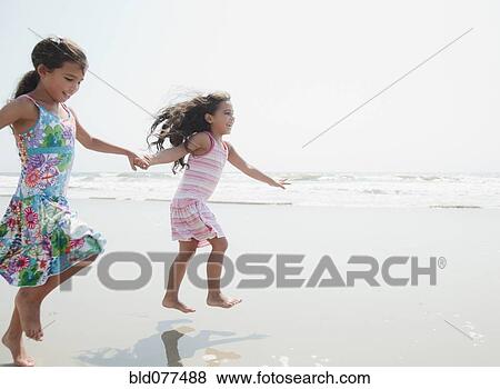 Stock Photo - Hispanic sisters playing at beach. Fotosearch