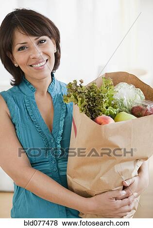 Stock Photo - Hispanic woman carrying groceries. Fotosearch