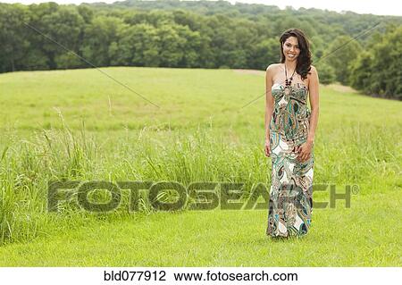 Stock Image - Hispanic woman in evening gown in field. Fotosearch