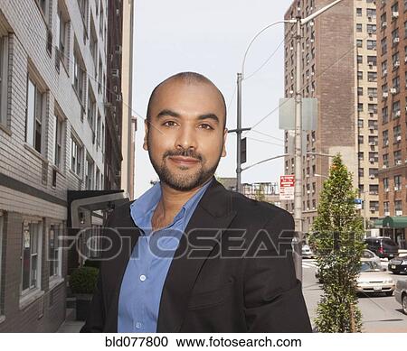 Stock Image - Mixed race businessman standing on urban street. Fotosearch
