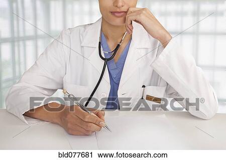 Stock Image - Mixed race doctor writing in hospital. Fotosearch