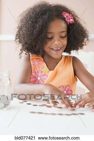 Stock Image - Mixed race girl counting coins. Fotosearch